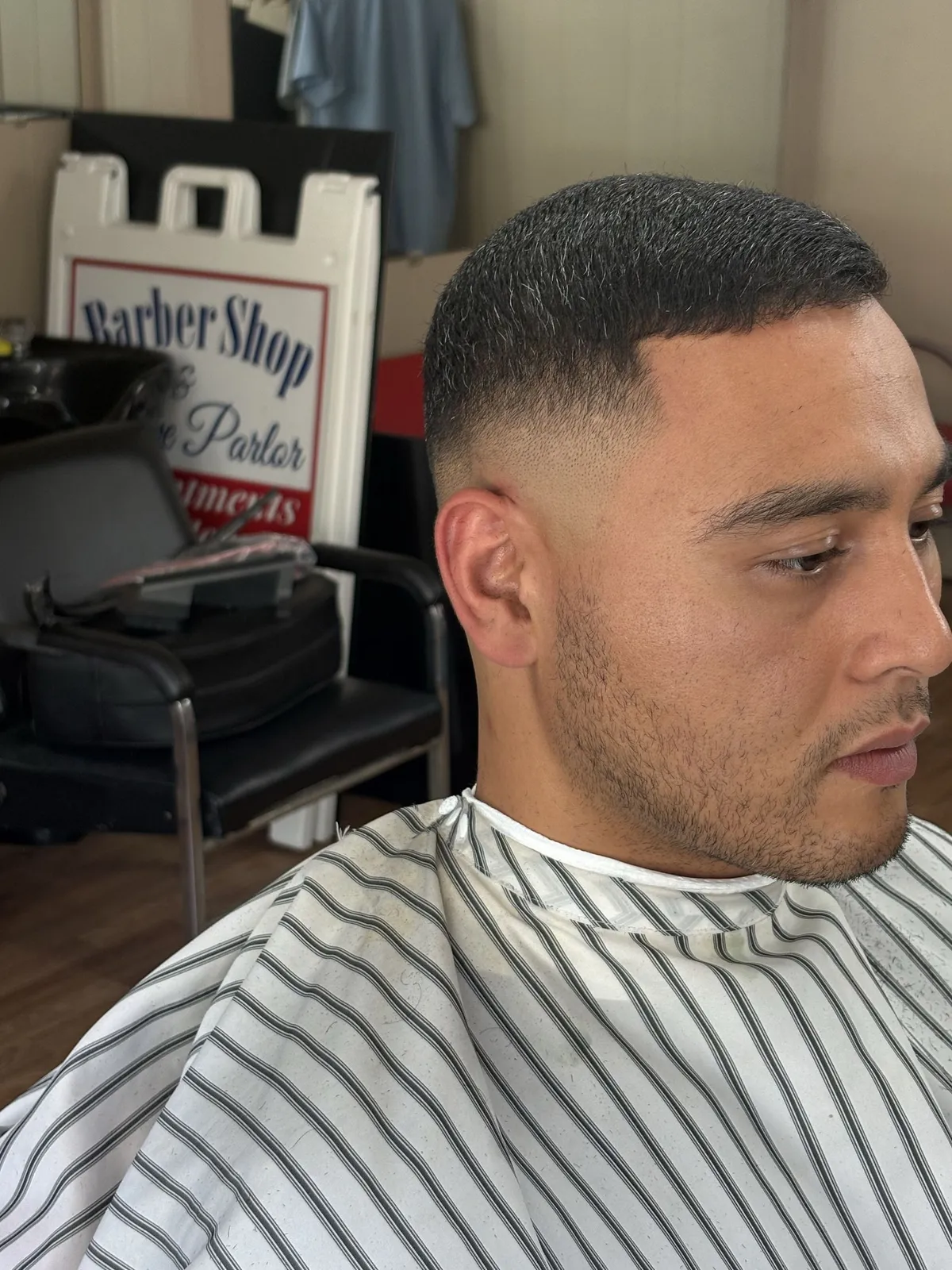 A man with a short dark crop, a low skin fade and a lined beard